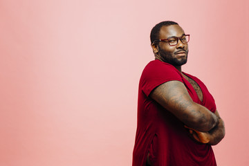 Portrait of a plus size man in red shirt and glasses, isolated on pink background - obrazy, fototapety, plakaty