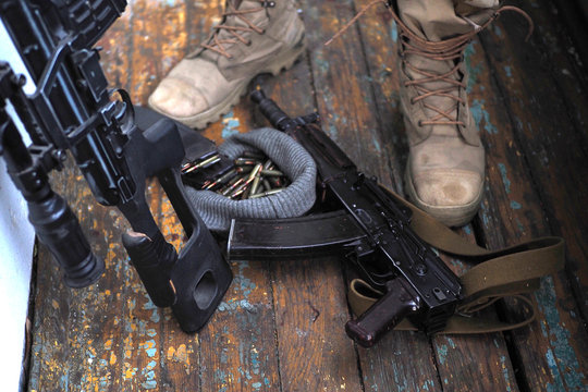 soldier feet and AK rifle on the floor close up.