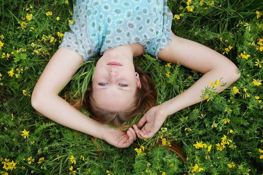 Upside Down Portrait Of Young Woman Lying In A Field Of Flowers