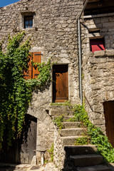 Eingangstür mit offener Treppe in einem sehr alten Natursteinhaus in dem mittelalterlichen Dorf Balazuc in Südfrankreich