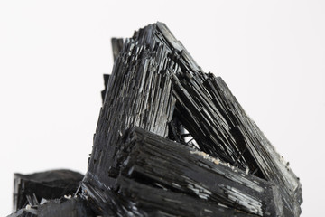 Extreme close up of black tourmaline mineral isolated over white background in focus stacking technique