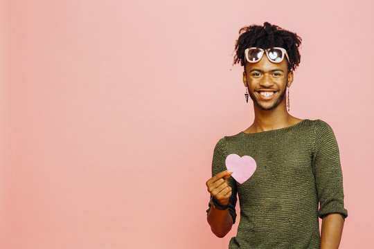 Portrait Of A Smiling Young Man Holding A Pink Heart, Isolated On Pink Studio Background