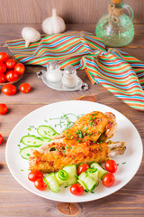 Baked turkey wing, cucumber slices and cherry tomatoes on a plate on a wooden table