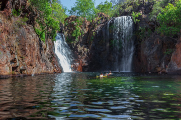 Fototapeta na wymiar Landscape view of young people swimming under Florence Falls in the Litchfield National Park, Northern Territory, Australia