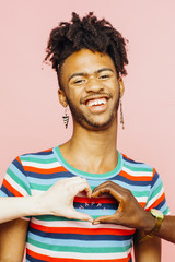 Portrait of a laughing young man with happy heart shaped on his shirt with hands