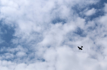 blue sky with white fluffy clouds with a flying airplane
