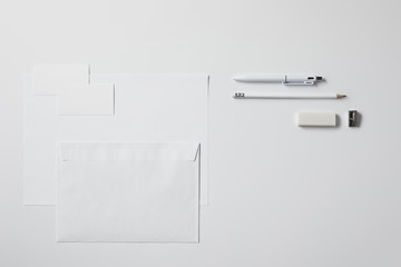 top view of various paper objects and office supplies on white surface for mockup
