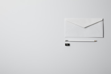top view of envelope with pencil and sharpener on white surface for mockup