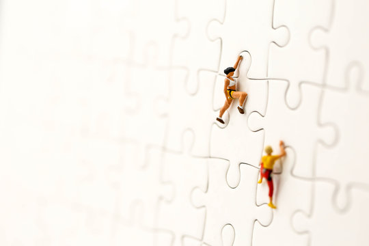 Miniature people : climbing  with challenging route on cliff of jigsaw puzzle, Concept of the path to purpose and success.