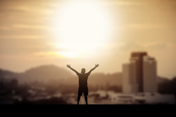 Man holding arms up in praise to God against sunrise at morning with city and vintage background. - obrazy, fototapety, plakaty