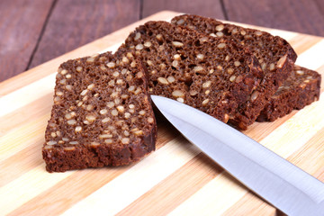 Fresh homemade bread and knife on wood background. Selective focus.