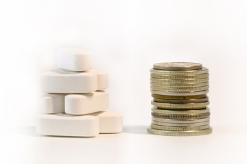 a stack of pills and a stack of coins on a light background