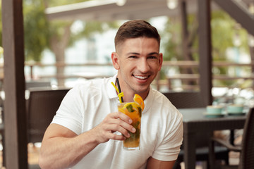 young man drinking cocktail in beach cafe