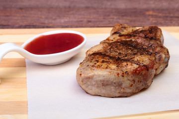 grilled pork chop with Cranberry sauce on plate on wooden board