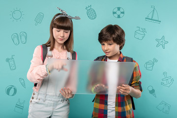 Checking the rout. Calm attentive teenagers standing with a futuristic transparent device in their hands and checking the rout on the screen of it