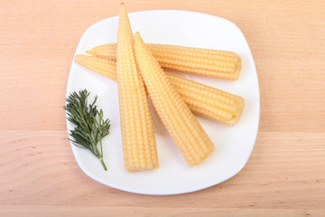 Mini Corn cob preserved on plate on wooden board.