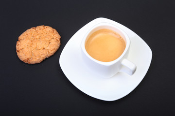 Classic espresso in white cup with homemade cake on black background. Selective focus.