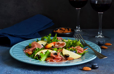 Salad with jamon, pears, blueberries and almonds. A glass of cold, red wine. Delicacy.