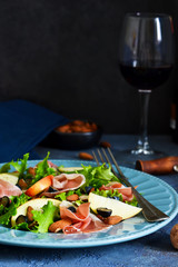 Salad with jamon, pears, blueberries and almonds. A glass of cold, red wine. Delicacy.