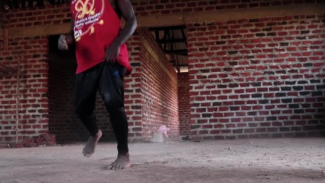 A young African youth wearing a mask break-dancing in a construction site.