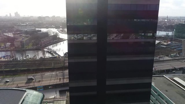 Aerial footage of Amsterdam city center moving over modern office building then showing Nieuwmarkt en Lastage neighbourhood NEMO Science Museum and The National Maritime Museum 4k high resolution