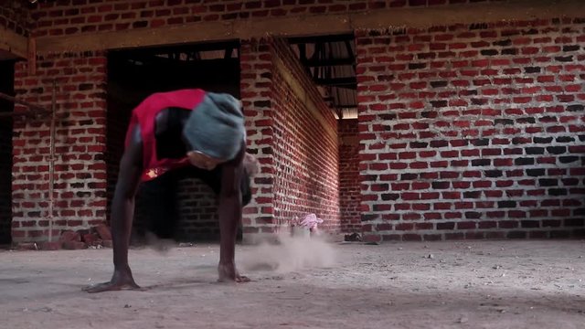 A young African youth wearing a mask break-dancing in a construction site in slow-motion