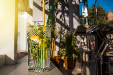 A glass of homemade lemonade with lemon stands on the windowsill