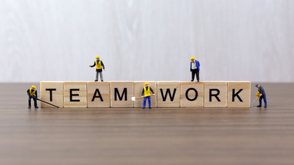 Miniature workers standing around wooden block of work teamwork words background. Business concept with copy space.