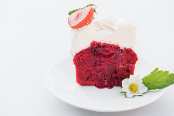 Cut cupcake red velvet with strawberry and cream on white plate. Close up