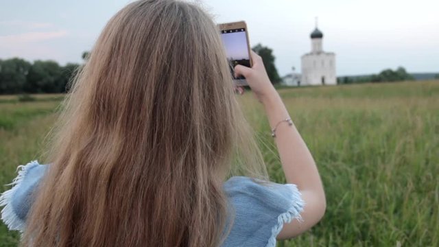 Back view of Young Beautifull Blond Woman travelling to Church of the Intercession on the Nerl. Vladimir region, Russia.