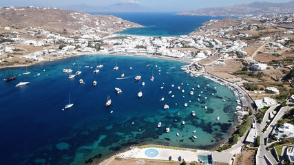 Aerial drone bird's eye view photo of famous organized with sun beds crystal clear water beach of Ornos in island of Mykonos, Cyclades, Greece