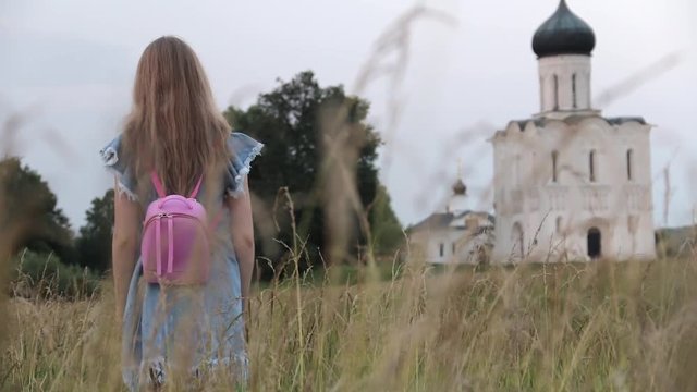 Back view of Young Beautifull Blond Woman travelling to Church of the Intercession on the Nerl. Vladimir region, Russia.