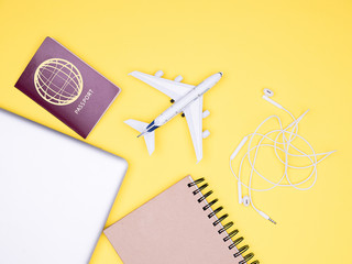 flat lay of traveler kit on yellow background , with passport with notebook and a laptop