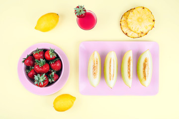 Fresh strawberries in bowl and melone on pastel yellow background.