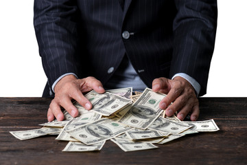 Pile of paper currency ..Man hands in pinstripe suit sweeping pile of US dollar banknotes on old...