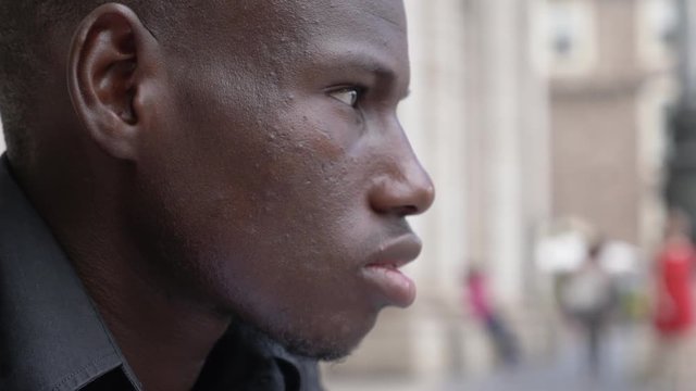 thoughtful youn amrican african man observing the city