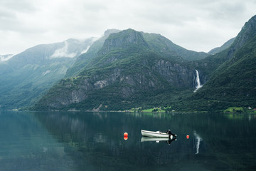 Landscape with a boat in the fjord and a waterfall in the mountains, Norway