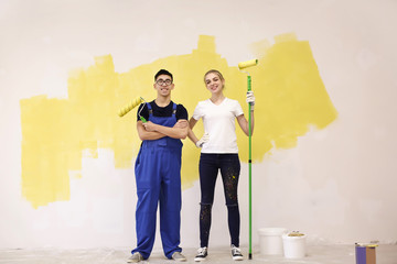 Professional decorators with paint rollers indoors