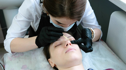 Cosmetologist rubs the client's eyelash with cotton swab. lash lamination.