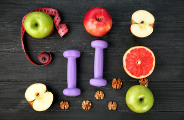 Fresh fruits and dumbbells on wooden background. Diet food