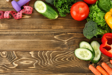 Fresh vegetables and dumbbell on wooden background, top view. Diet food © Pixel-Shot