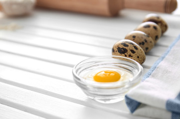 Bowl with yolk and quail eggs on kitchen table. Bakery workshop