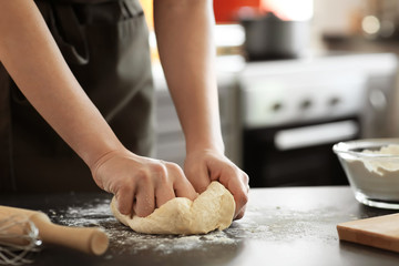 Baker kneading dough on kitchen table