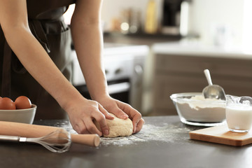 Baker kneading dough on kitchen table