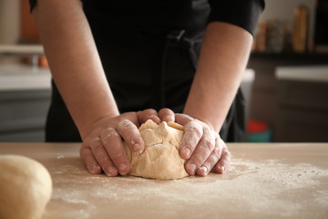 Fototapeta premium Baker kneading dough on kitchen table