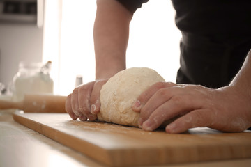 Baker kneading dough on kitchen table