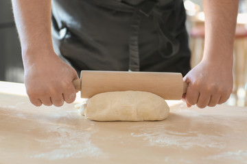 Baker rolling dough on kitchen table