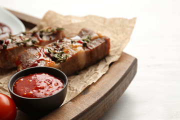 Delicious barbecue sauce and grilled meat on wooden board, closeup