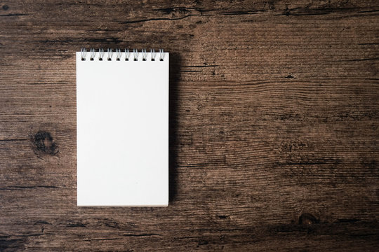 Top view image of open notebook with blank page on the wooden table..