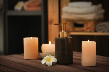 Burning candles and cosmetic product on table in spa salon